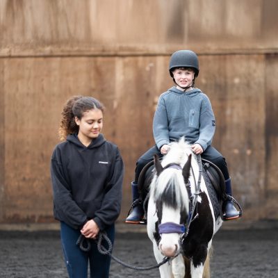 A young boy smiles as he rides a pony at the Bourne Vale Stables Open Day near Birmingham