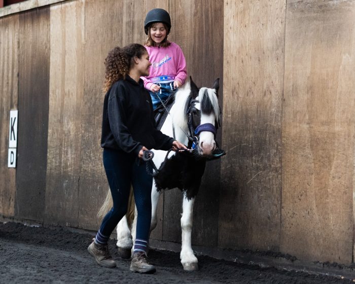 A young girl with happy smile as she rides a pony at Bourne Vale Stables near Birmingham